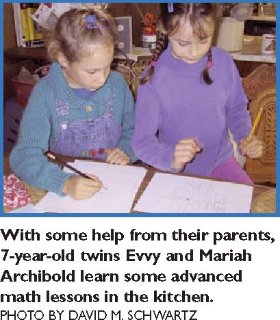 With some help from their parents, 7-year-old twins Evvy and Mariah Archibold learn some advanced math lessons in the kitchen. PHOTO BY DAVID M. SCHWARTZ